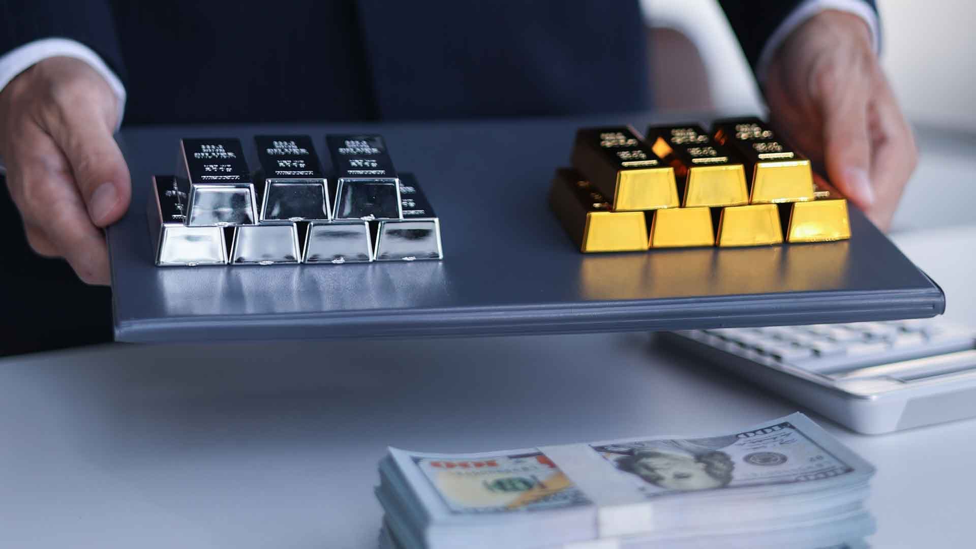 Suited professional presenting gold and silver bullion bars